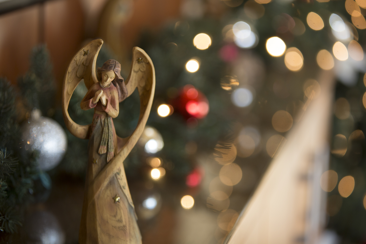 An angel Christmas ornament on a decorated tree.